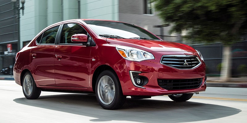 A Red Mitsubishi Mirage-G4 running on city road right side view