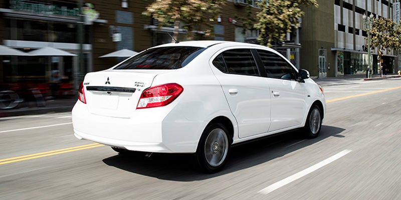 A White Mitsubishi Mirage-G4 running on road rear view